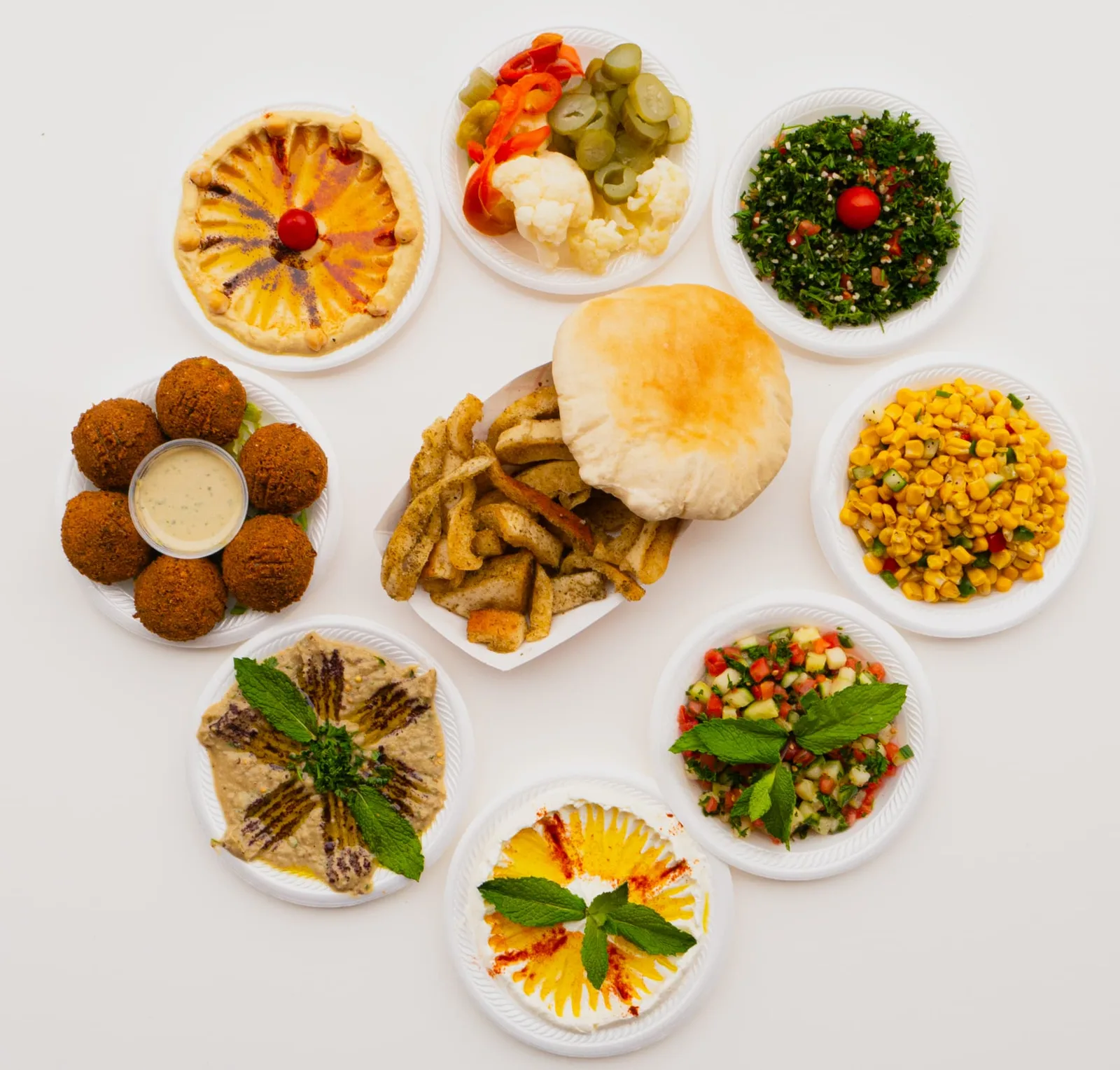 Overhead food photograph of Mediterranean plates including hummus, falafel, tabbouleh and pita, photographed by John, a Brand With Care creative partner