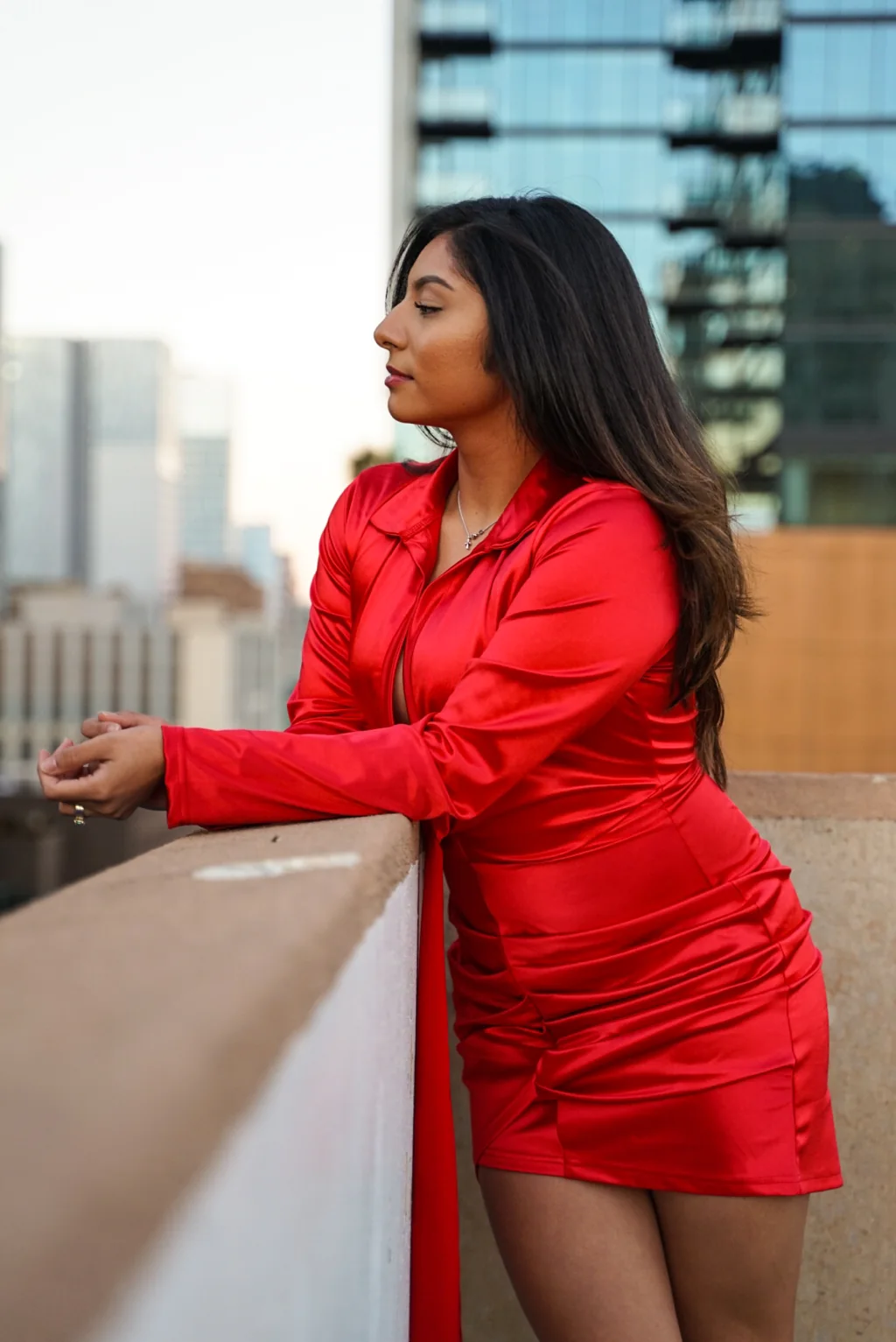Woman in a red dress posing on a terrace overlooking the city