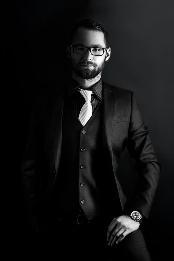 Black-and-white business portrait of a man wearing a suit and glasses