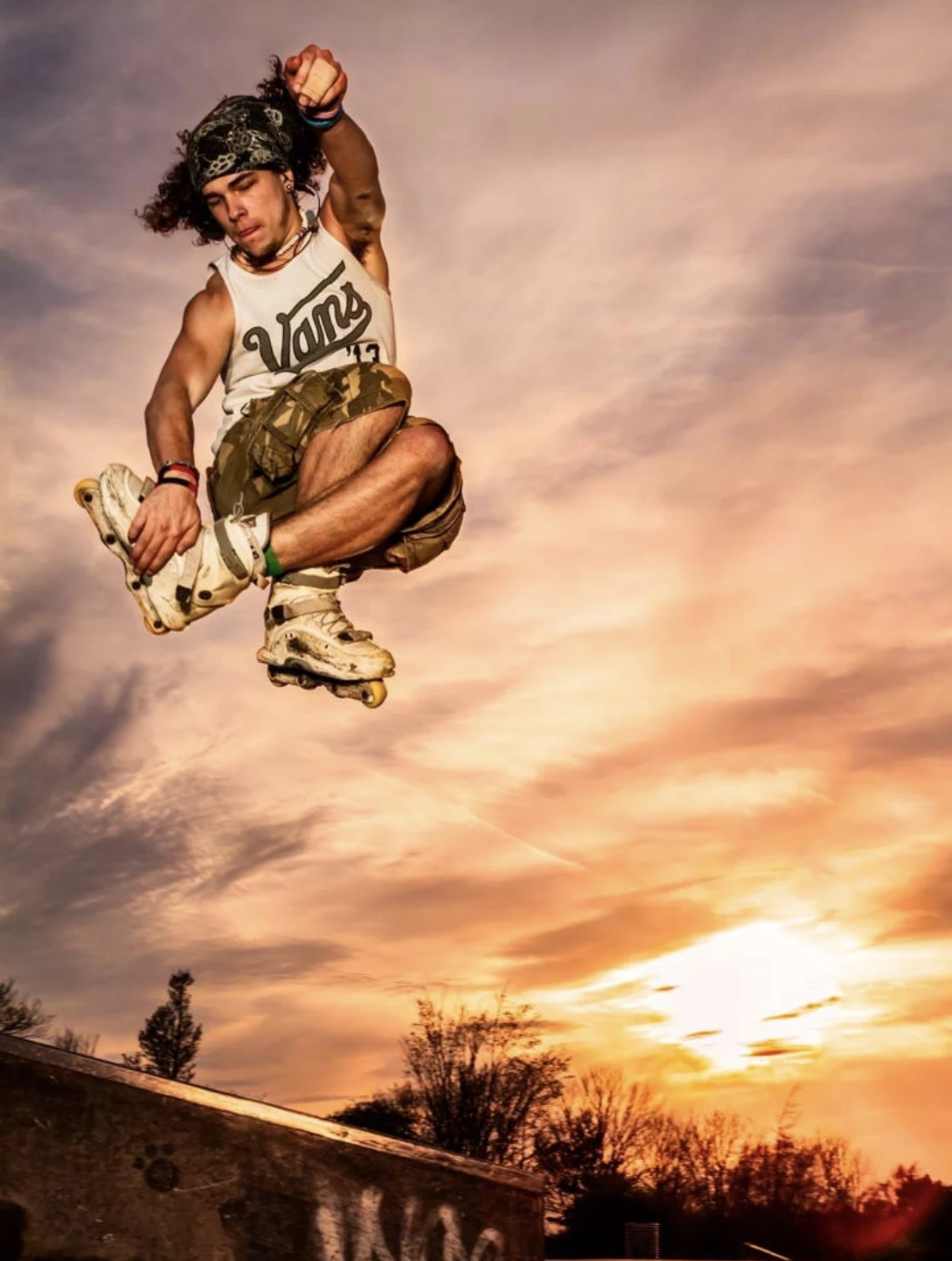Inline skater performing an aerial trick against a dramatic sunset sky