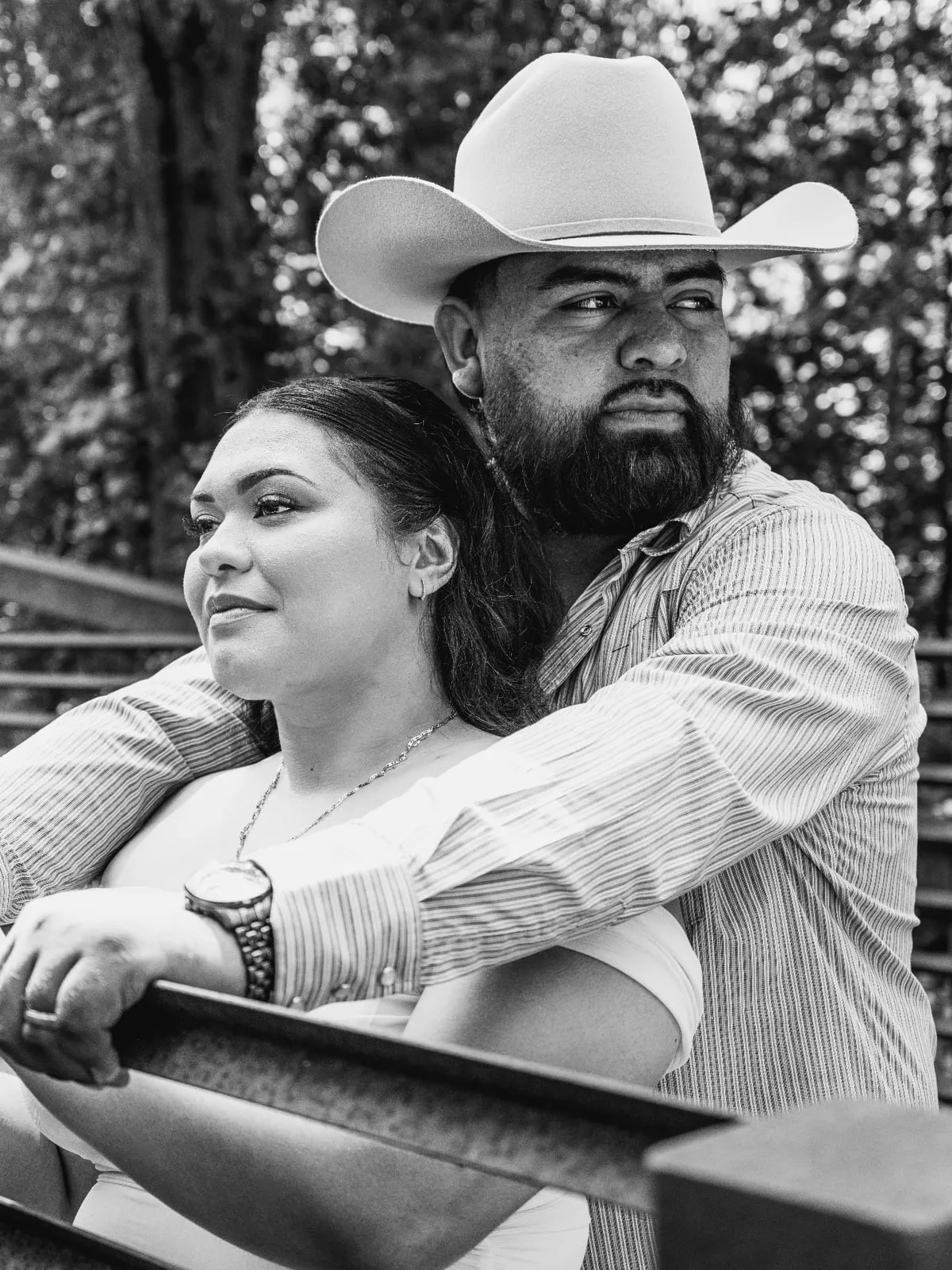 Black-and-white outdoor portrait of a couple seated together on bleachers, photographed by John, a Brand With Care creative partner