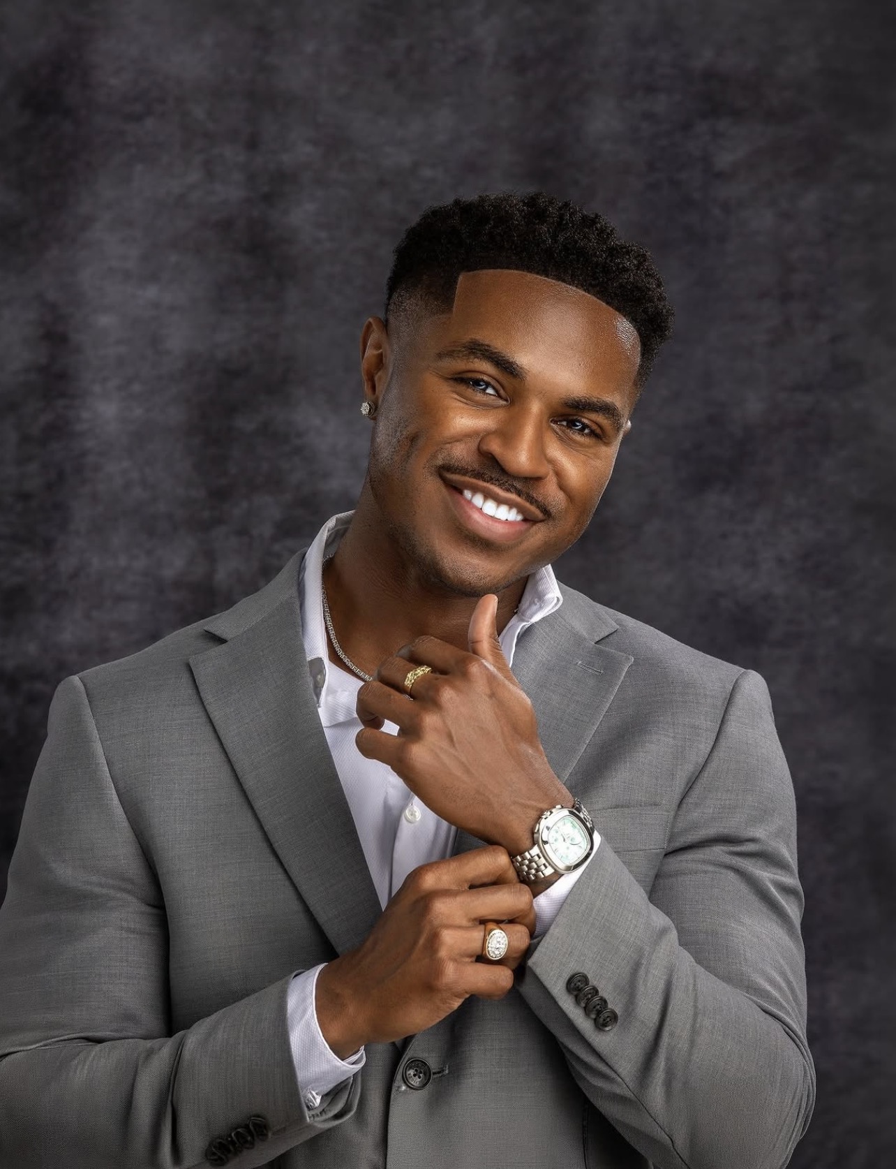 Studio headshot of a smiling man in a grey suit