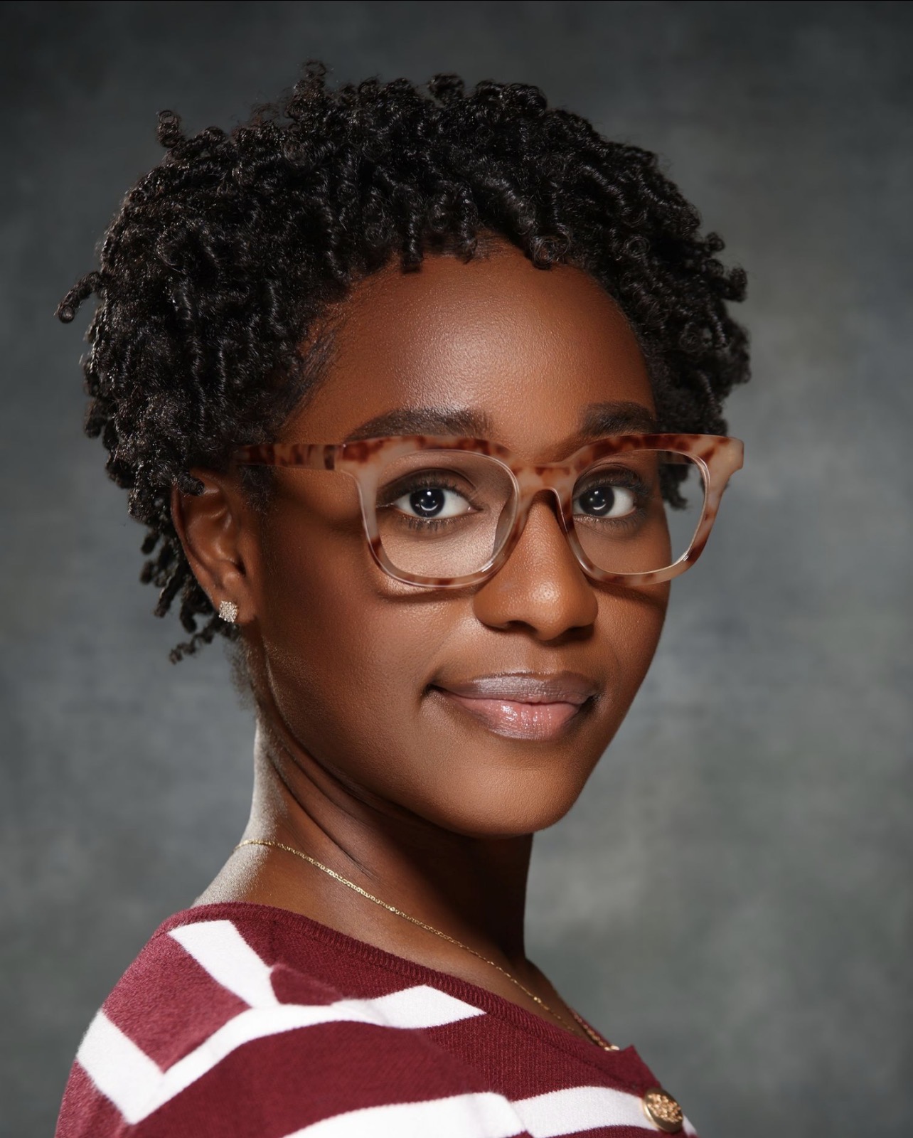 Studio headshot of a woman with glasses on a grey backdrop