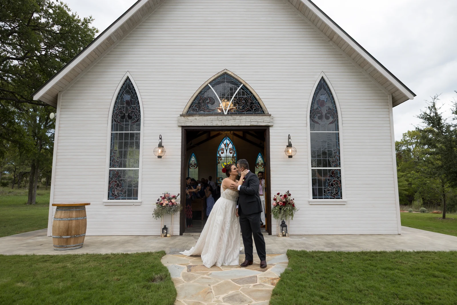 Newlyweds sharing a kiss outside a white chapel photographed by Anthony