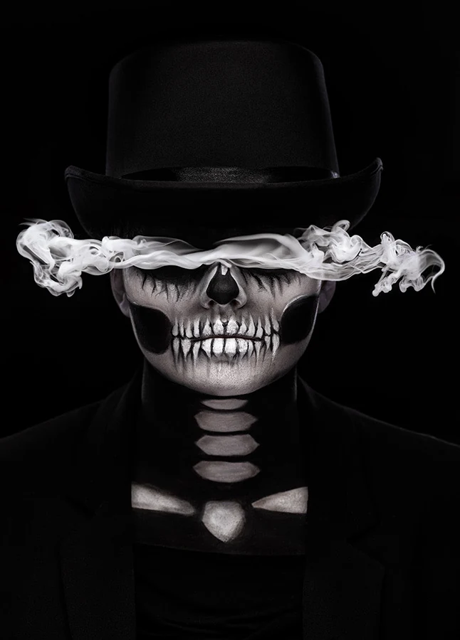 Monochrome studio portrait with skeleton makeup, top hat and a band of smoke