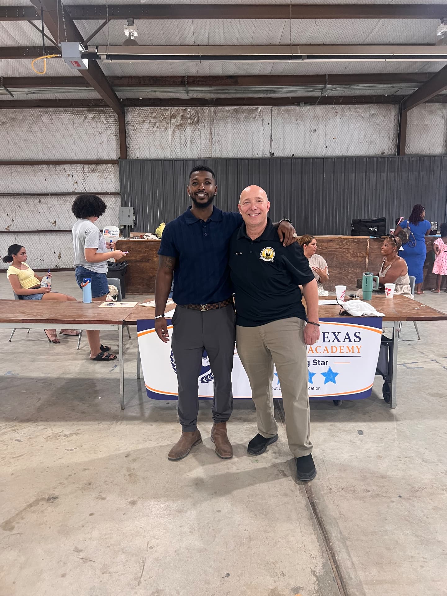 Event portrait of two community leaders at a Central Texas academy booth, photographed by IVAN