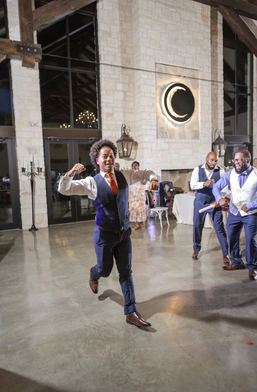 Guest dancing on the floor of a stone and timber reception venue at night
