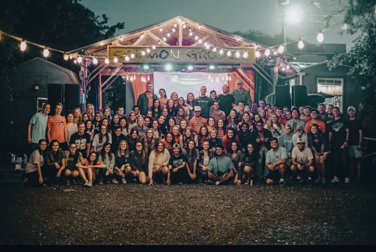 Large group portrait outdoors at night under string lights