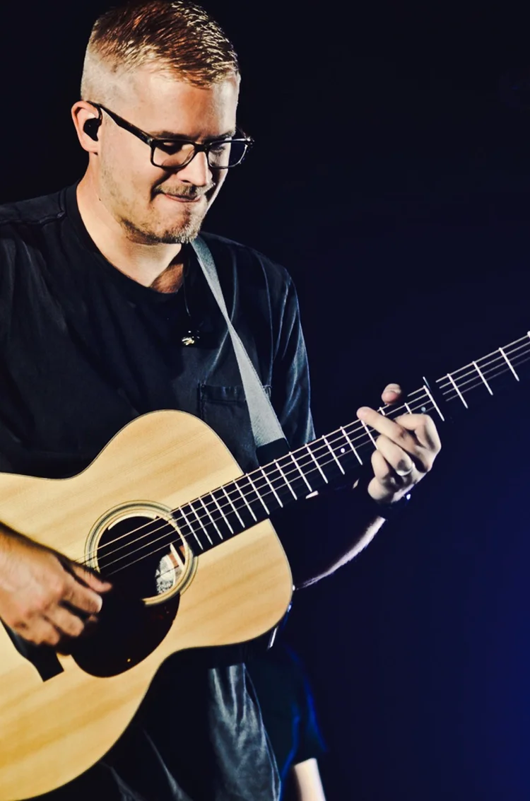 Guitarist playing an acoustic guitar under stage lighting