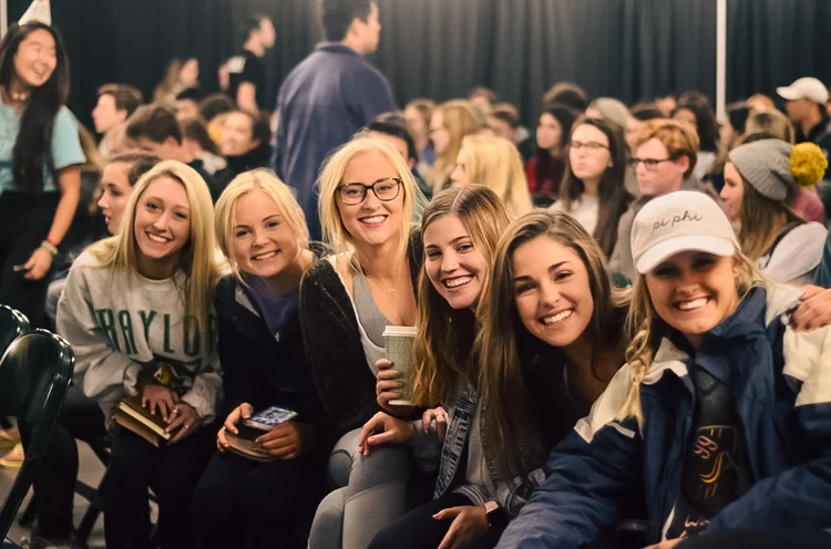 Group of friends smiling together while seated at an indoor event