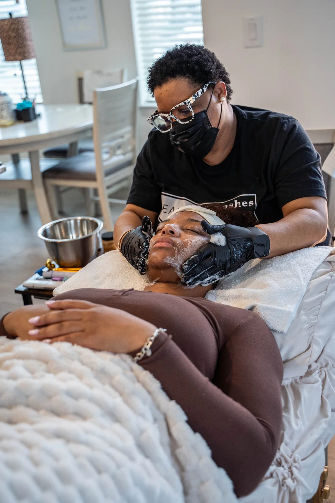 Skincare professional providing a facial treatment in a home studio