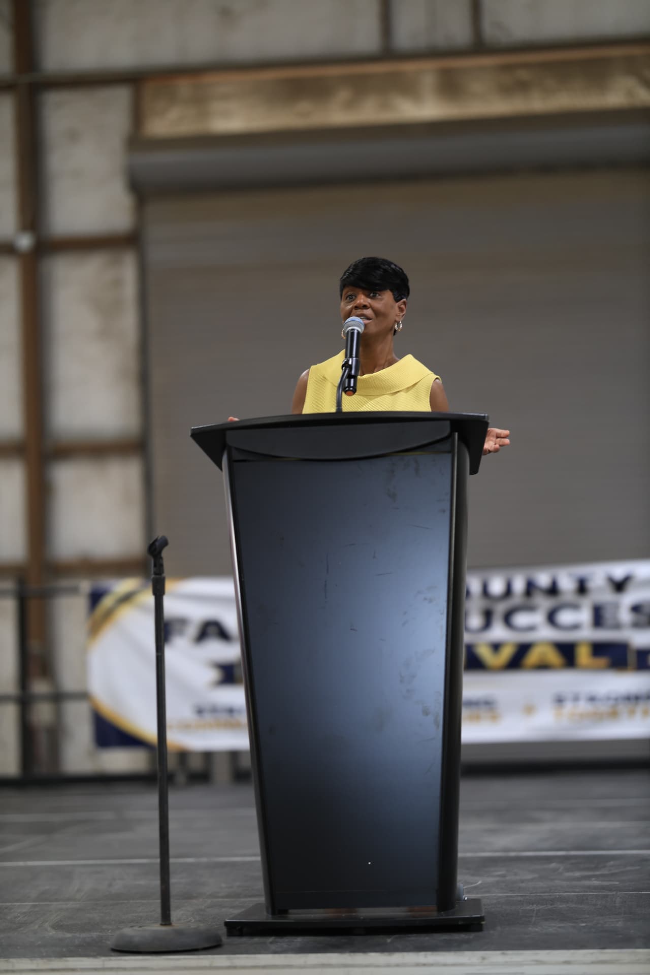 Guest speaker at the podium during a county success festival, photographed by IVAN