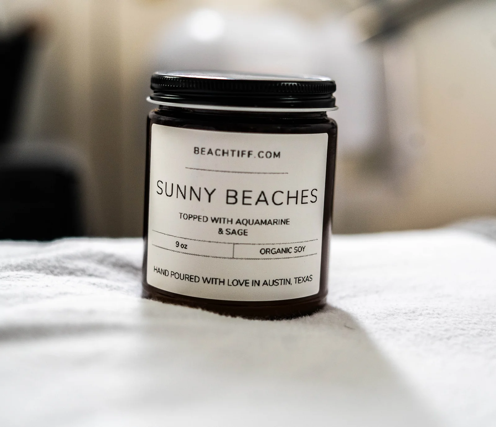 Hand-poured Sunny Beaches candle arranged for a product photograph