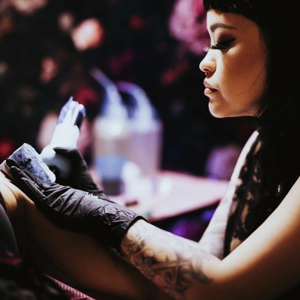 Moody branding photograph of a tattoo artist at work in a dimly lit studio