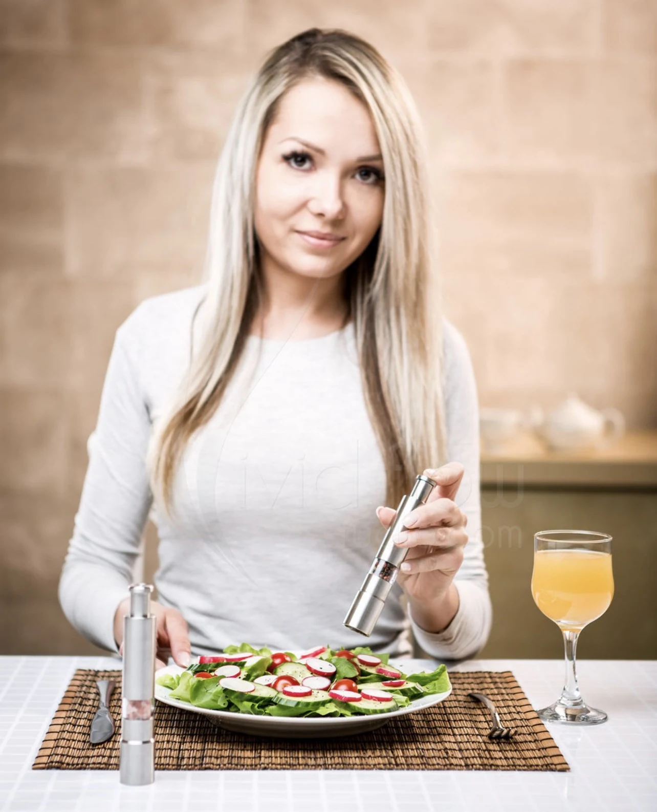 Lifestyle photograph of a woman seasoning a fresh salad by Marcin
