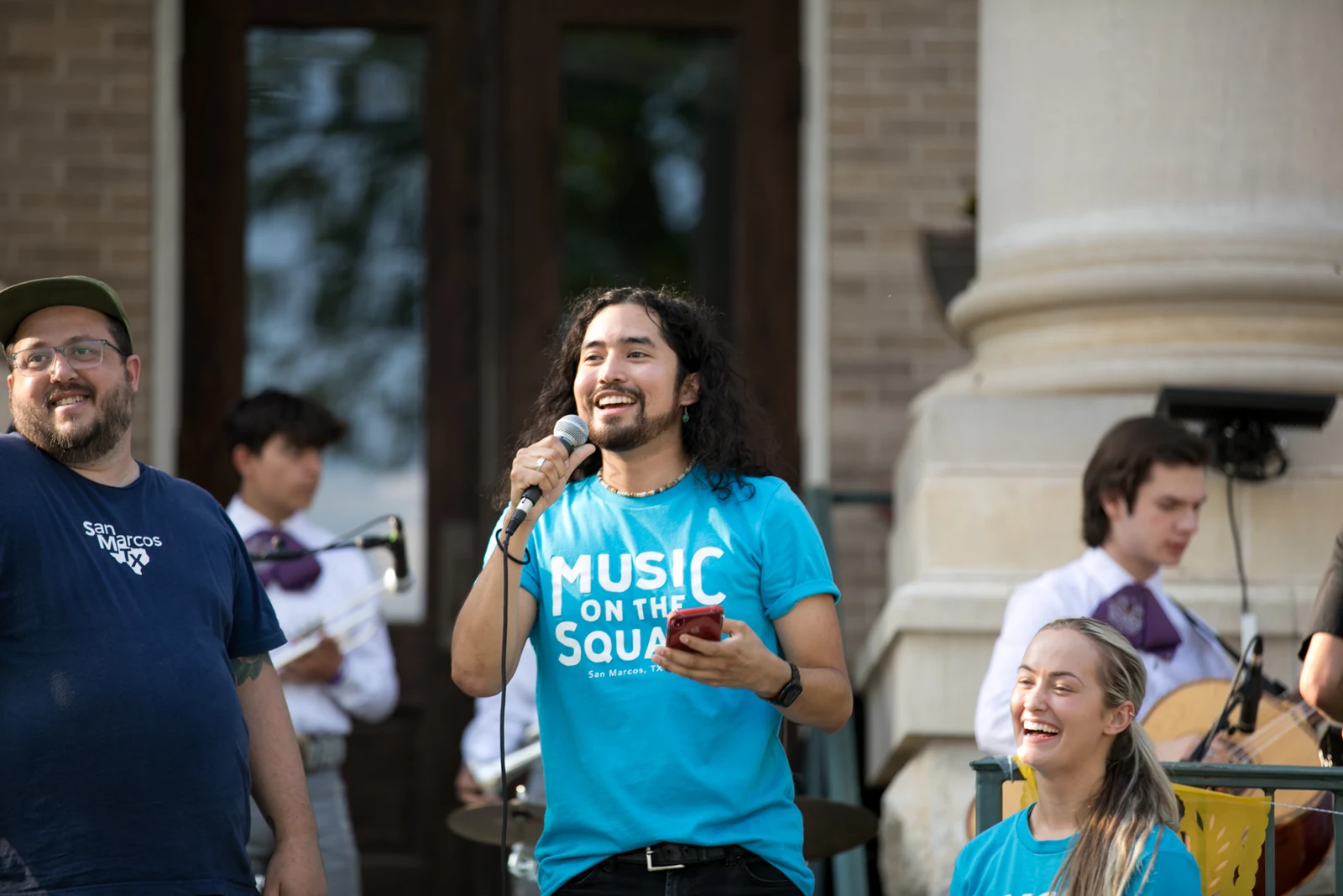 Community event host speaking into a microphone photographed by Anthony