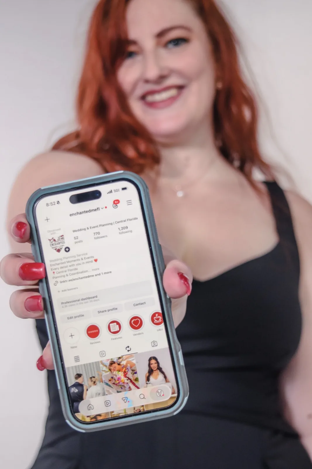 Content creation photograph of a smiling woman holding out a phone showing a social media profile