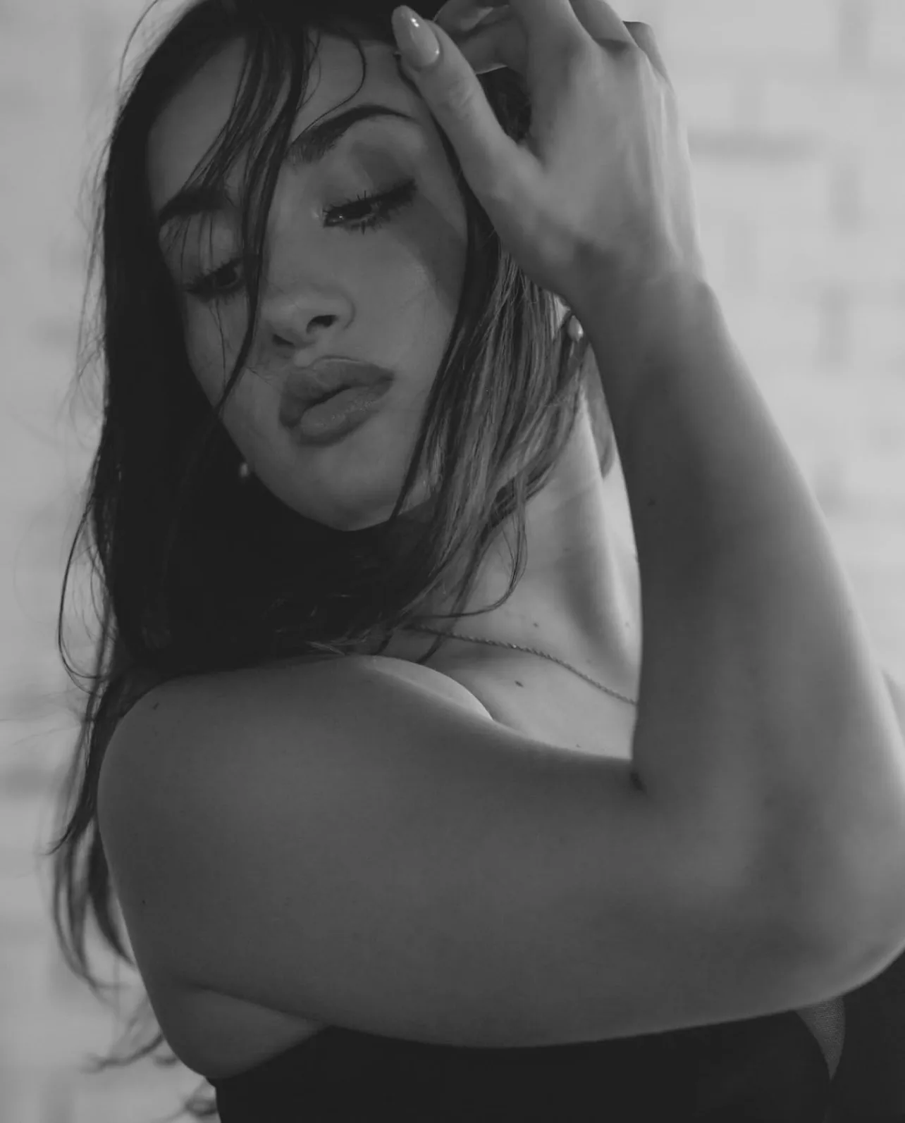Black and white close-crop beauty portrait of a woman with her hand in her hair