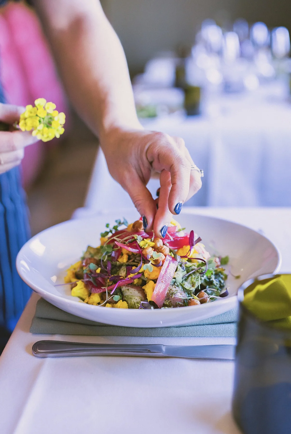 Event food photograph of a plated salad being garnished by LORENA