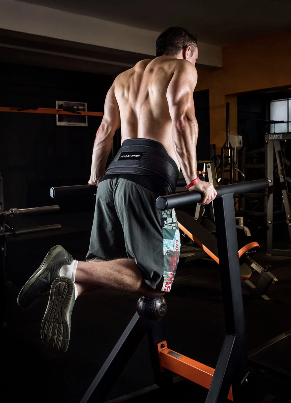 Athletic fitness portrait of a man training on parallel bars in a gym