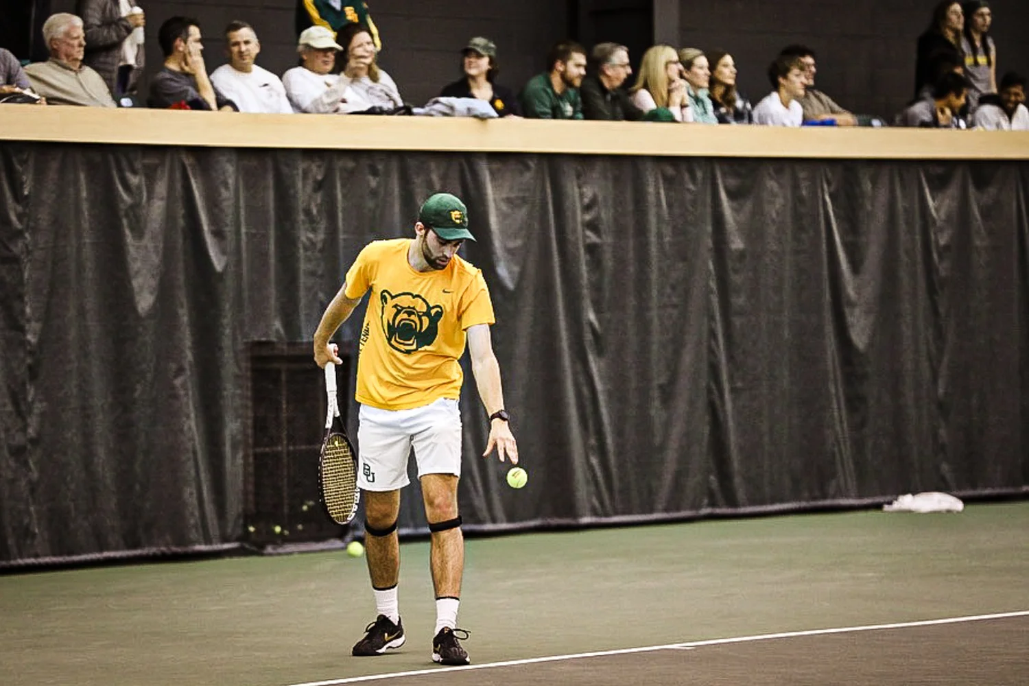 Tennis player bouncing a ball before serving with spectators in the stands